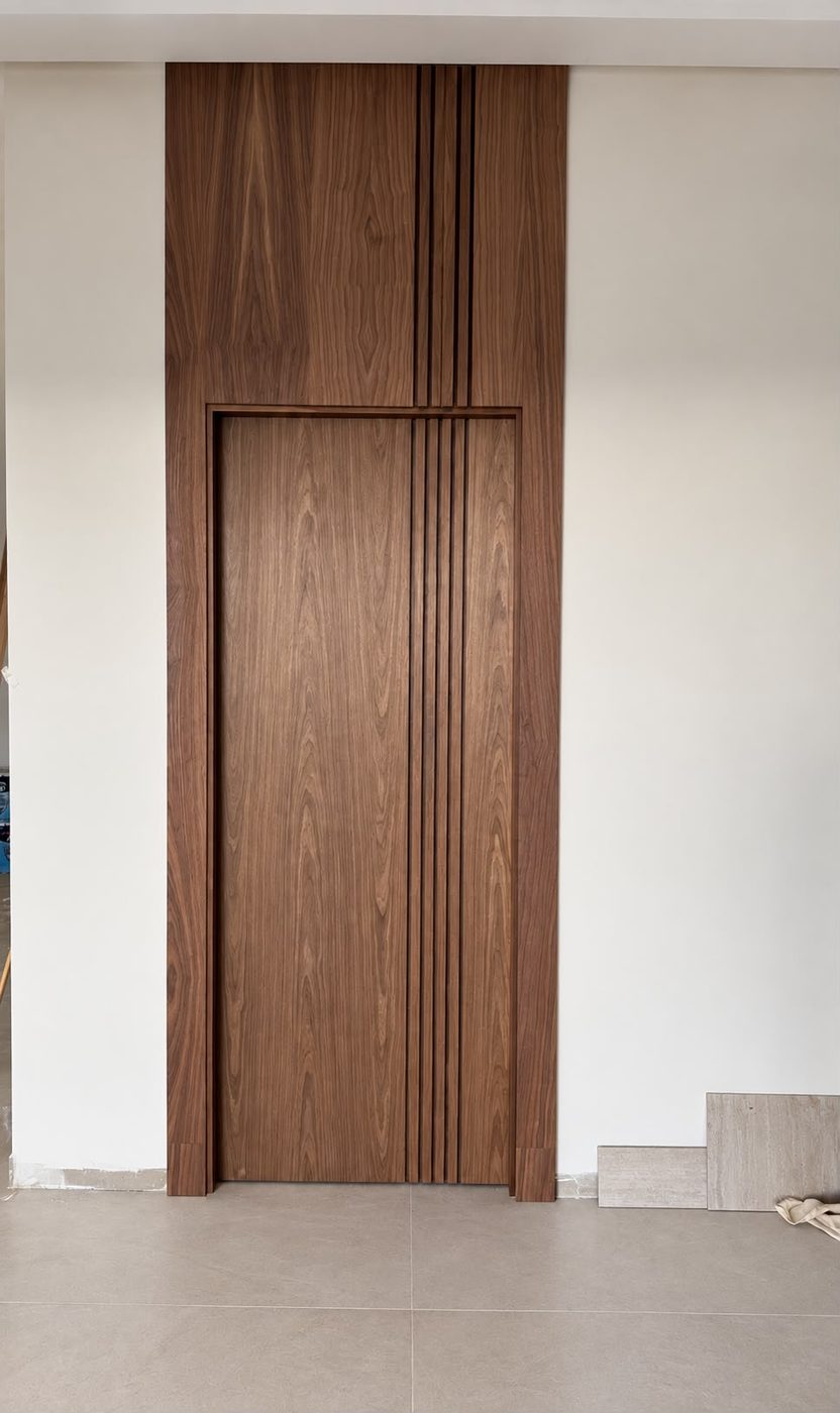 Walnut door set into a full-height fluted wood feature panel
