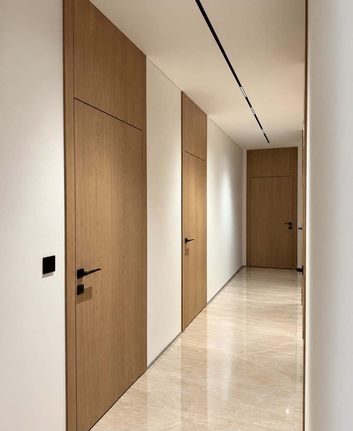 Full-height flush walnut doors along a marble-floored corridor
