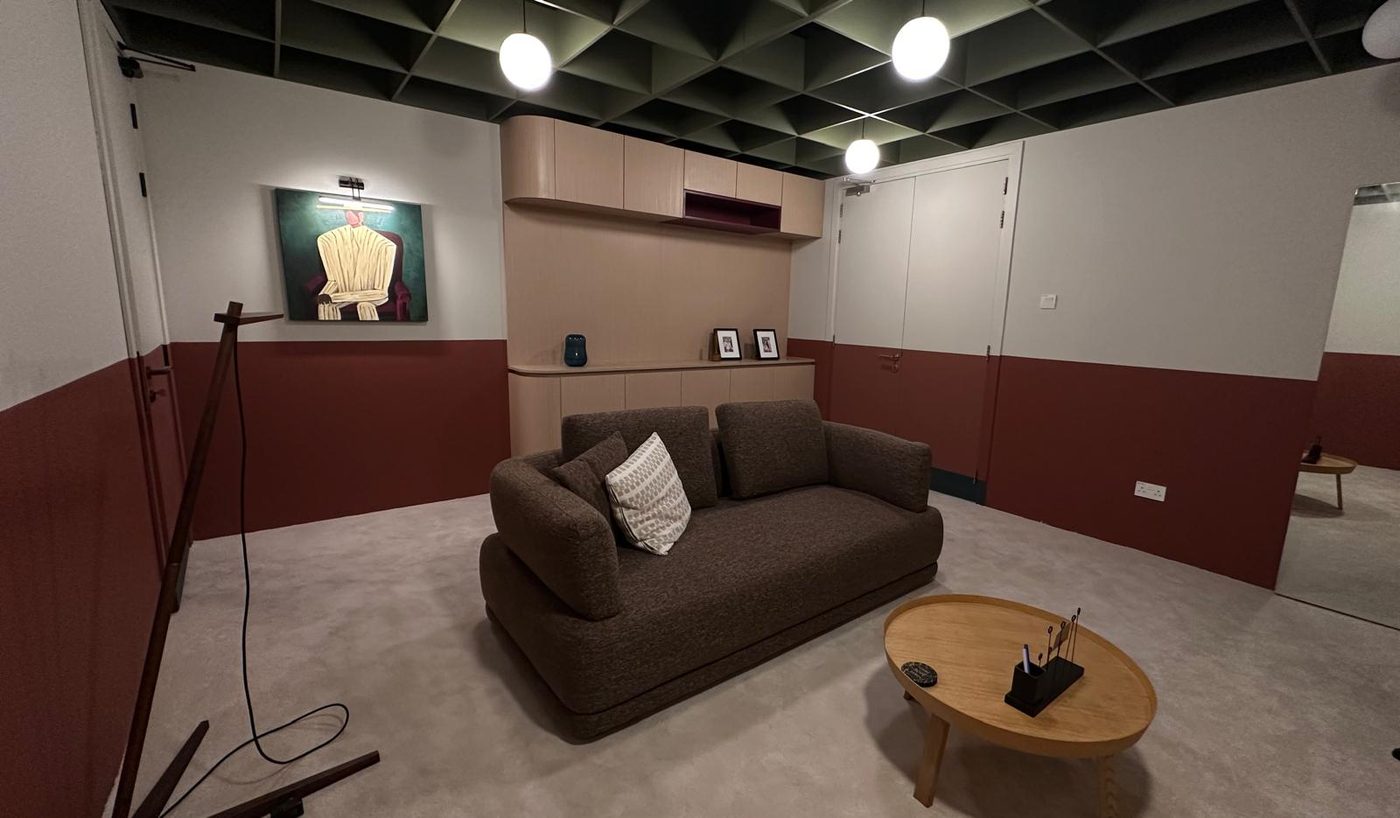 Corporate office lounge with a built-in light-oak storage and display unit, sofa and round coffee table
