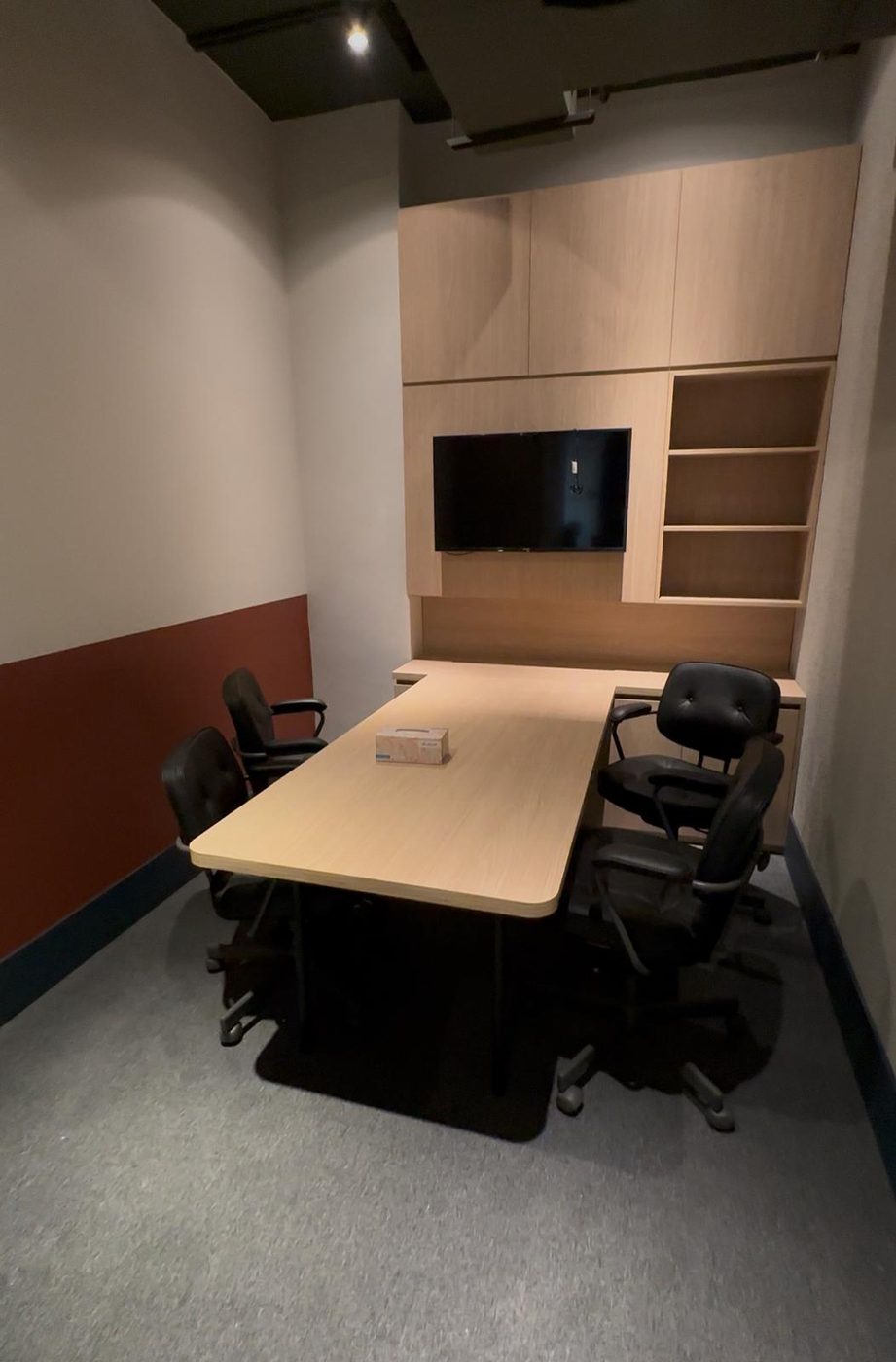 Corporate meeting room with a custom oak table and a wall unit with a TV and open shelves
