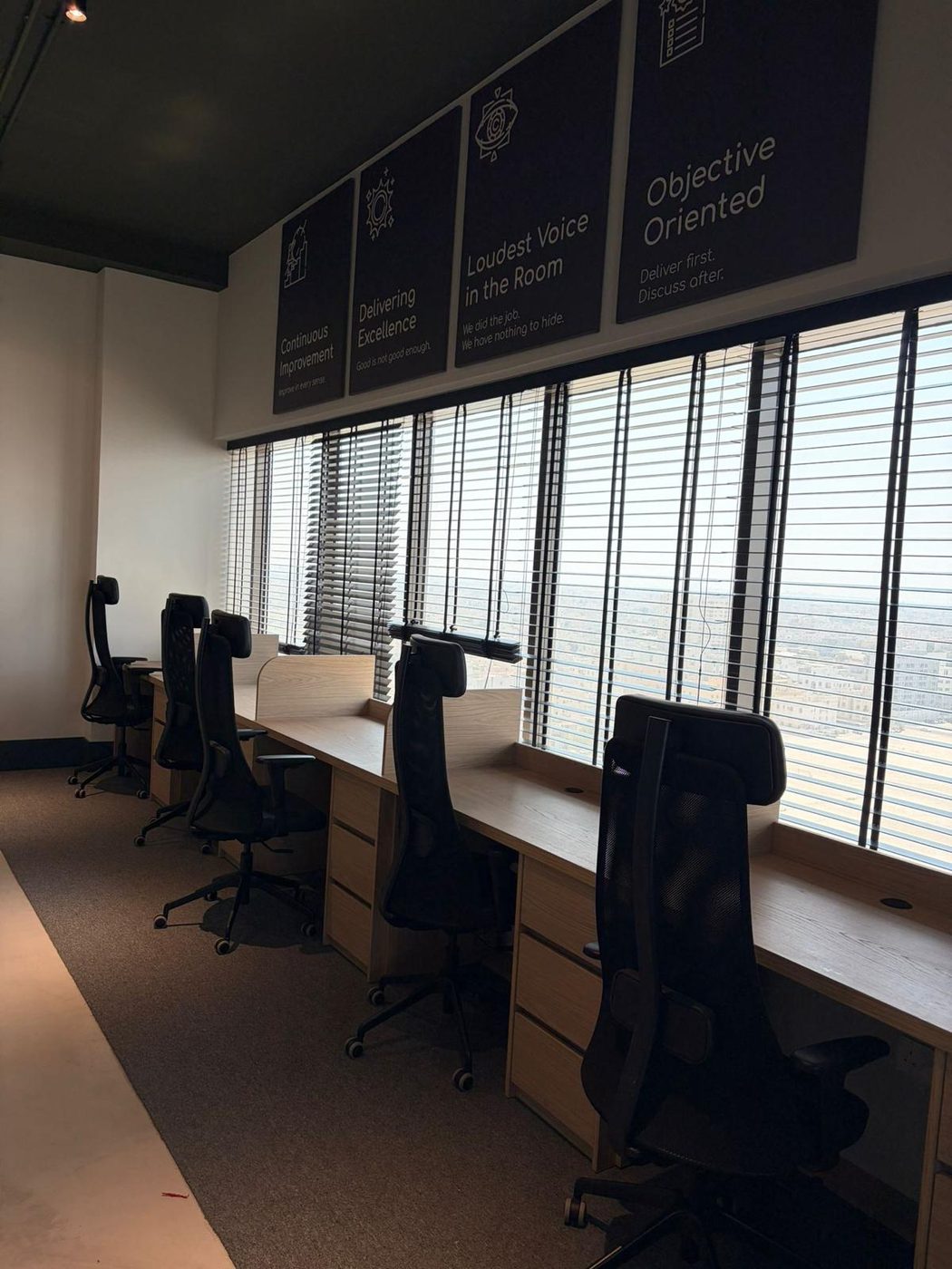 Row of window-side oak workstations with built-in drawer units in a corporate office