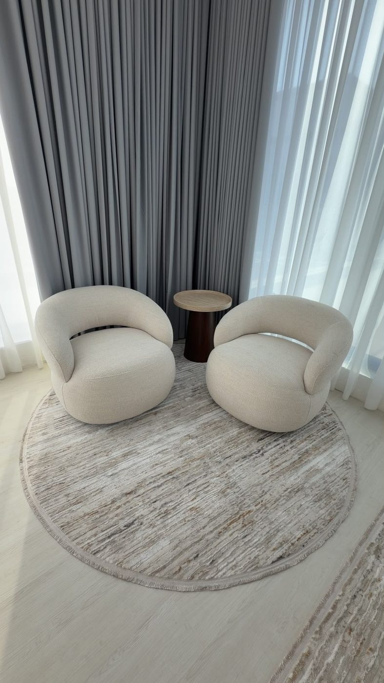 Seating corner with two cream lounge chairs and a round side table on a circular rug
